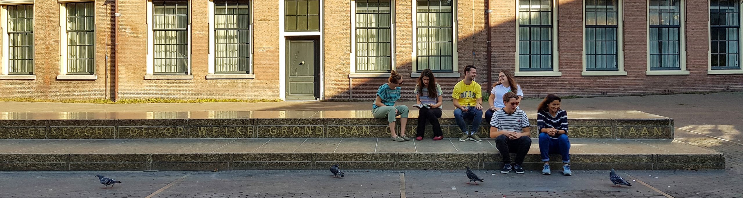 Jongeren zitten op de 45 meter lange Grondwetbank te Den Haag